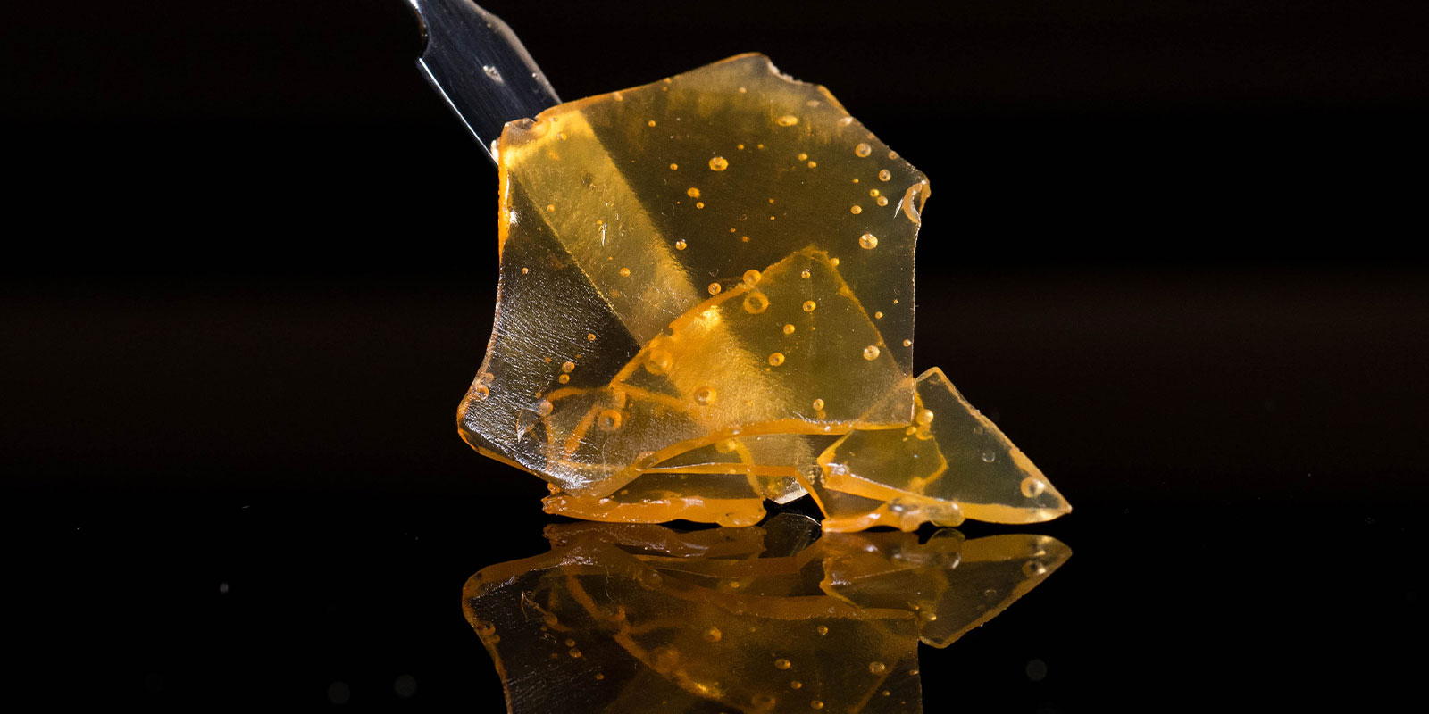 close up of cannabis resin on a black background using a stick