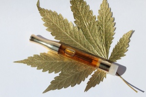 cannabis cartridge sitting on top of a gold cannabis leaf