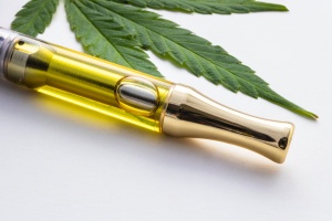 Cannabis Cartridges next to a weed flower on a white background