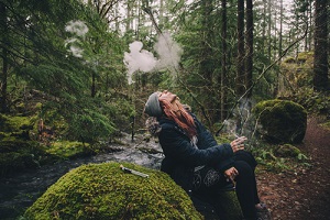 blonde woman smoking cannabis while hiking in the woods getting Weed Hangover 