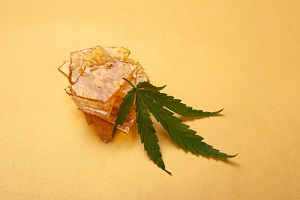 pieces of yellow cannabis wax and green leaf
