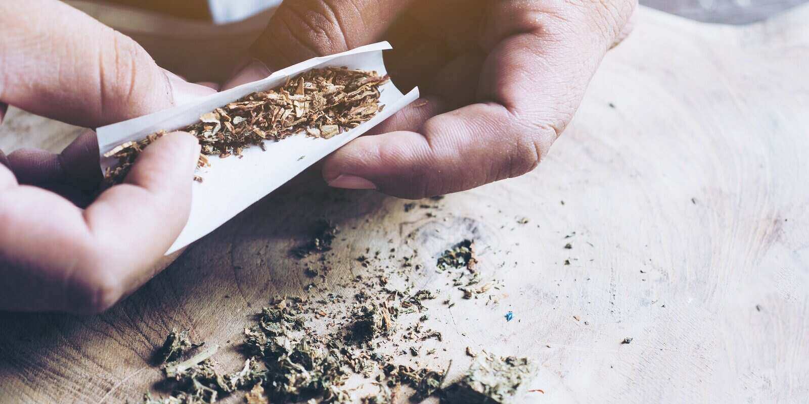 hands of man rolling a joint marijuana cannabis joint