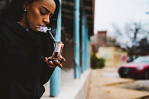 Woman smokes cannabis out of glass bubbler outside