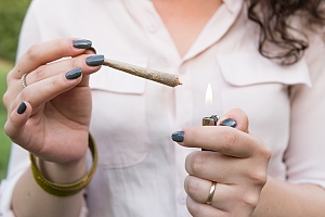 Woman holding weed preroll with black painted nails