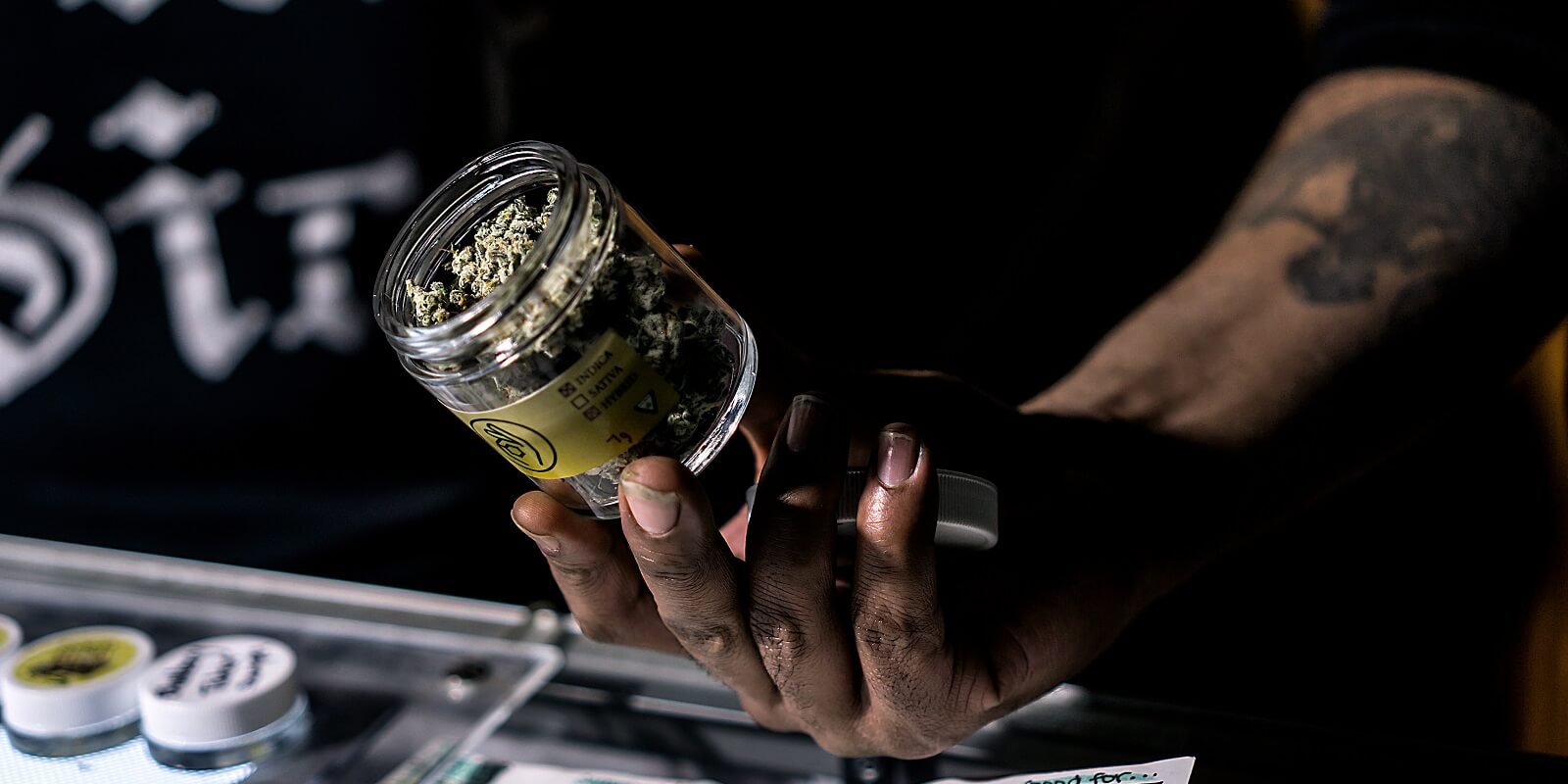 a vendor showing off a jar of cannabis flowers