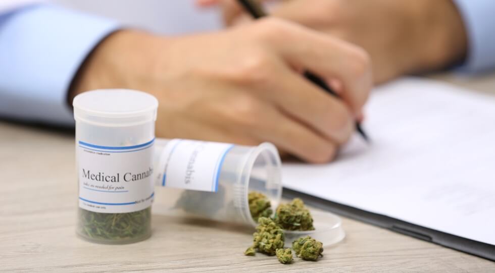 doctor writing on prescription blank and bottle with medical cannabis on table close up