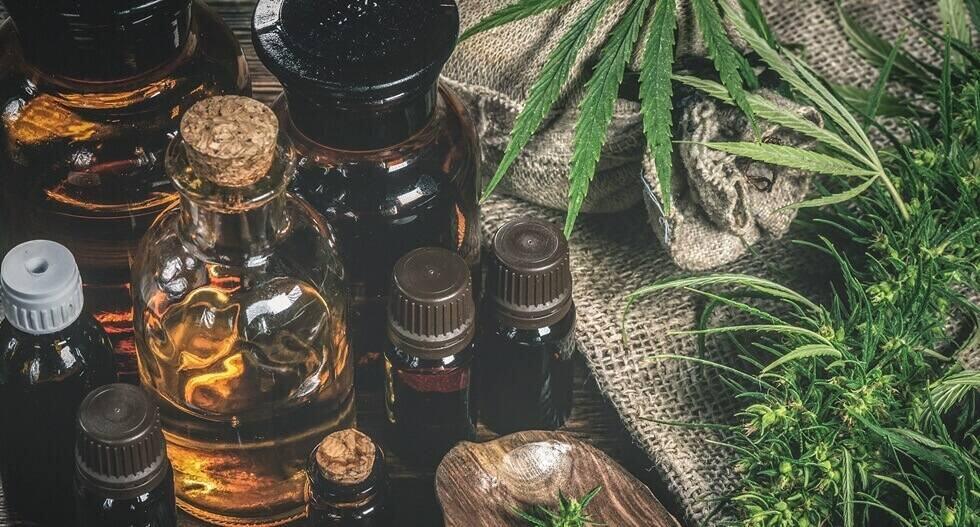 oil bottles and green plant of cannabis on a wooden background