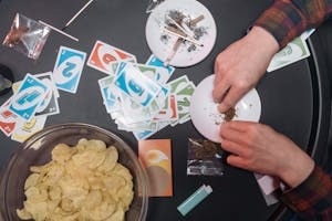 Man Holding Weed on A Plate Near Snacks Bowl on Table